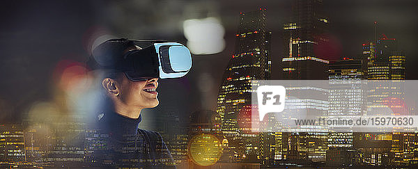 Lächelnde Geschäftsfrau mit Virtual-Reality-Brille in der Stadt bei Nacht