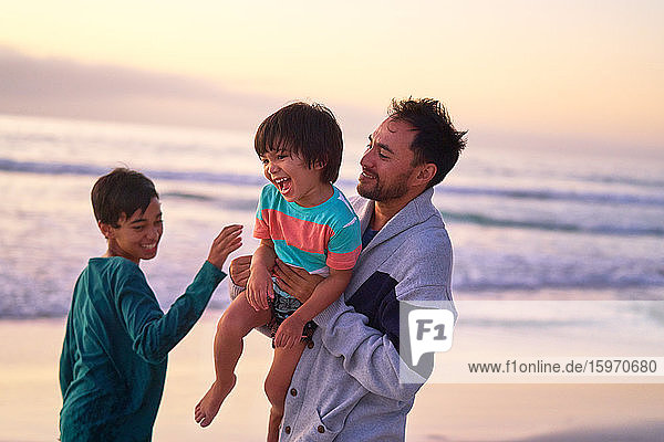 Happy father and sons playing on ocean beach