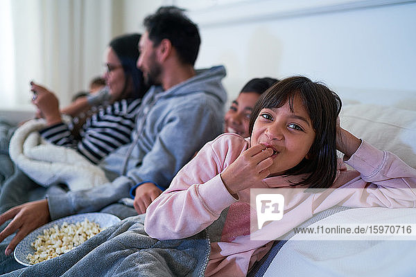 Portrait happy girl eating popcorn on sofa