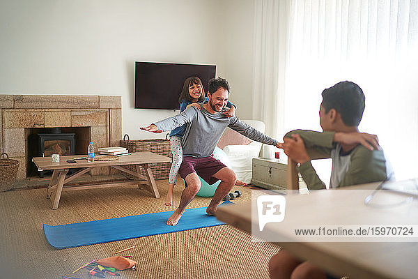 Playful father and daughter exercising in living room