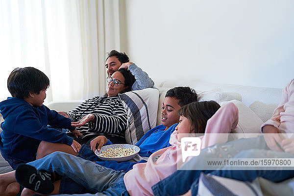 Familie entspannt sich und isst Popcorn auf dem Wohnzimmersofa