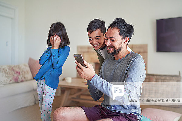 Vater und Kinder benutzen Smartphone im Wohnzimmer