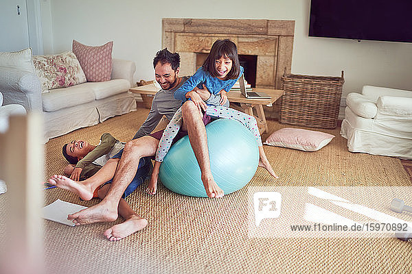 Playful father and kids on fitness ball in living room
