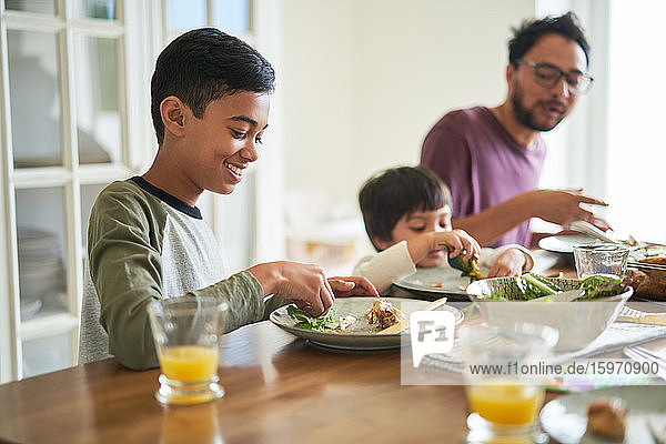 Smiling boy eating dinner with family at table