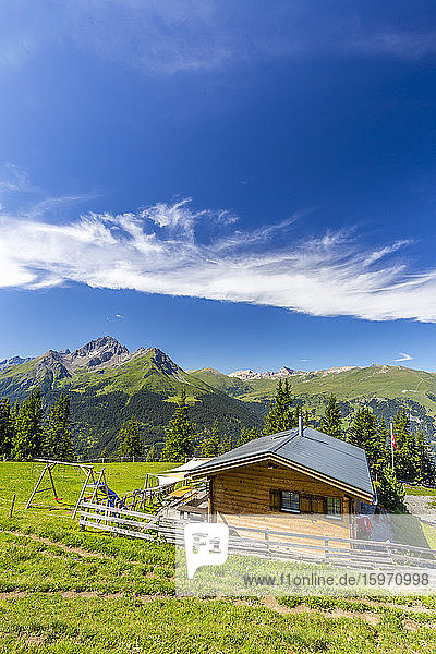 Almhütte mit Schweizer Fahne  unter herrlichen Wolken. Surses  Surselva  Graubünden  Schweiz  Europa