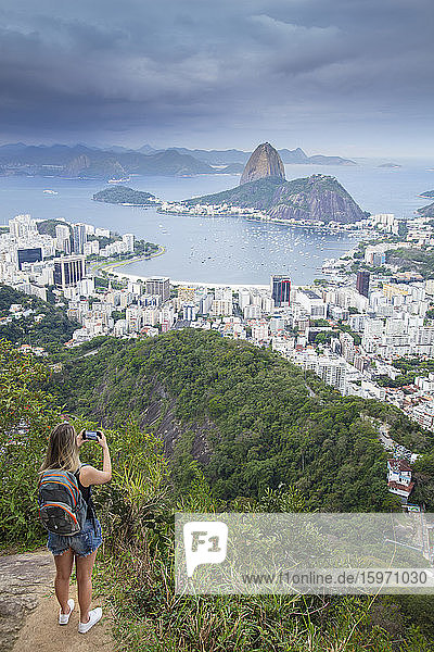 Eine Wanderin mit Blick über die Landschaft von Rio zum Zuckerhut vom Tijuca-Nationalpark  Rio de Janeiro  Brasilien  Südamerika