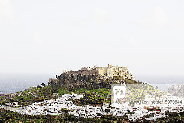Weiße Häuser unterhalb der befestigten Zitadelle der Akropolis von Lindos auf Rhodos  Dodekanes  Griechische Inseln  Griechenland  Europa
