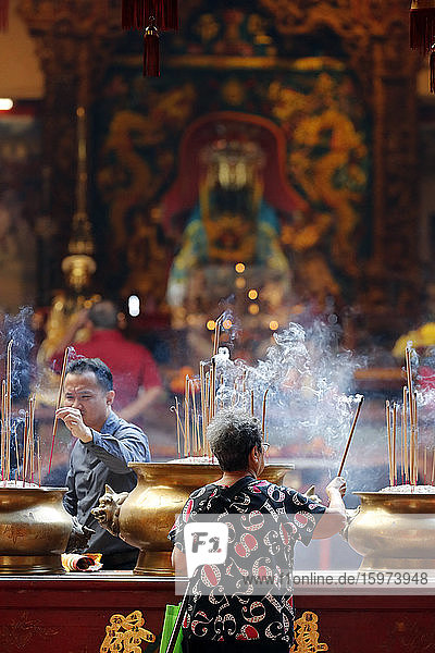 Chinese man burning incense and praying to a prosperous future  Guan Di Chinese Taoist Temple  Kuala Lumpur  Malaysia  Southeast Asia  Asia