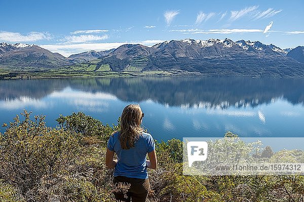 Junge Frau blickt über den See Lake Wakatipu  Berge spiegeln sich im See  Otago  Südinsel  Neuseeland  Ozeanien