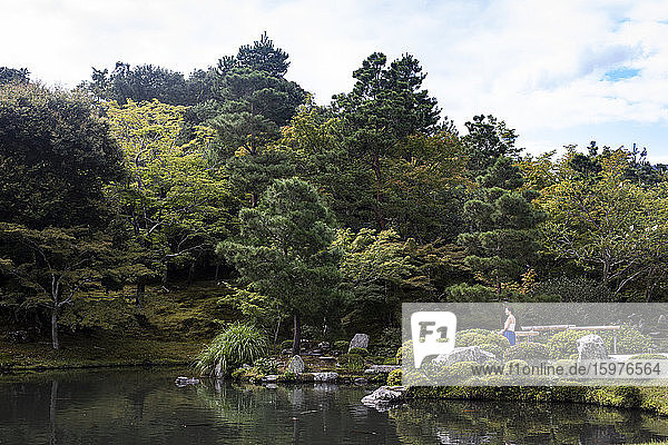 Japan  Präfektur Kyoto  Kyoto  Junge Frau meditiert vor dem Sogen-Teich