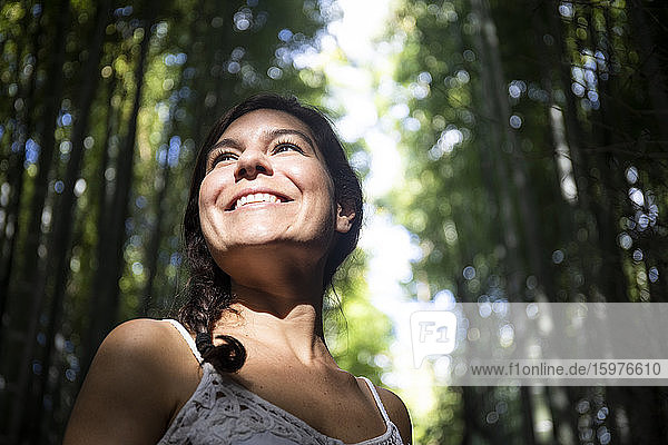 Japan  Tokyo  Low angle portrait of young woman standing in bamboo grove