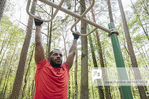 Sportler beim Üben am Klettergerüst im Wald