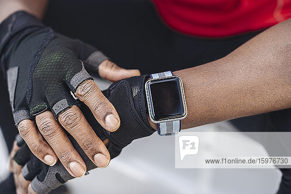 Nahaufnahme eines Sportlers mit Smartwatch und Handschuhen
