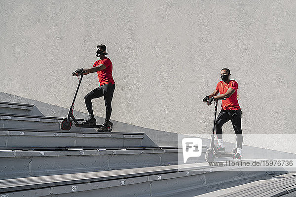 Sportsmen wearing face masks with scooters on stairs