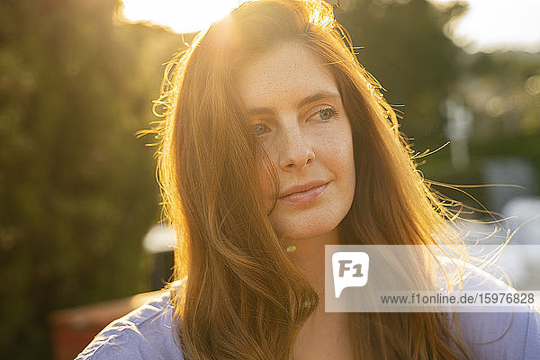 Porträt einer rothaarigen Frau  die seitwärts gegen die Sonne blickt