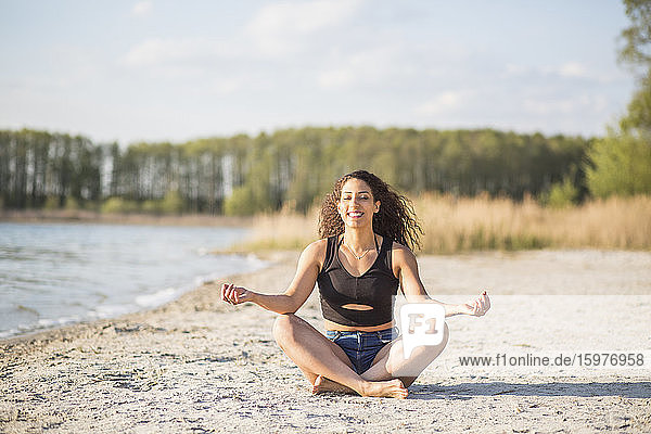 Portrait of young woman doing yoga exercise on the beach