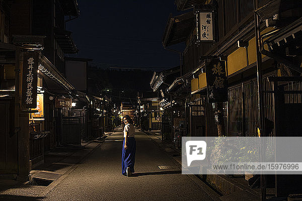 Japan  Takayama  Einsame Frau geht zwischen Reihen traditioneller japanischer Häuser bei Nacht