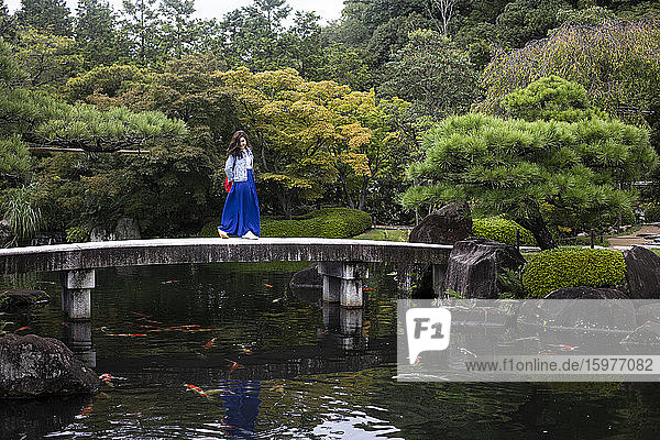 Japan  Himeji  Frau auf Fußgängerbrücke in Adelaide Himeji Gardens