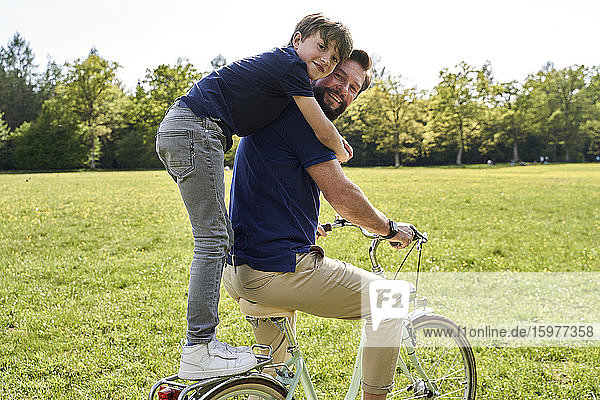 Happy boy embracing father while enjoying bicycle ride on sunny day