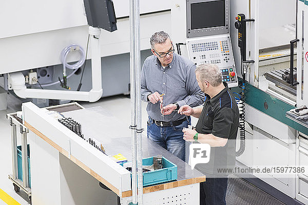 Two men talking at a machine in a factory