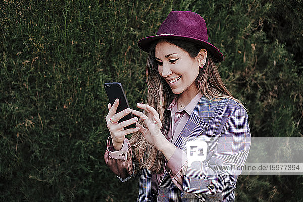 Porträt einer modischen Frau  die ihr Smartphone im Freien benutzt