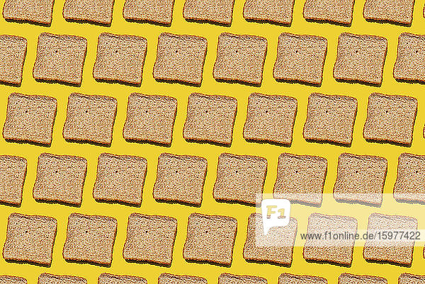 Pattern of slices of wheat bread against yellow background