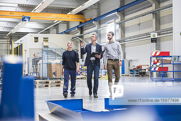 Two men and a woman walking in a factory