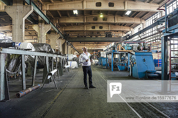 Senior businessman in a factory hall