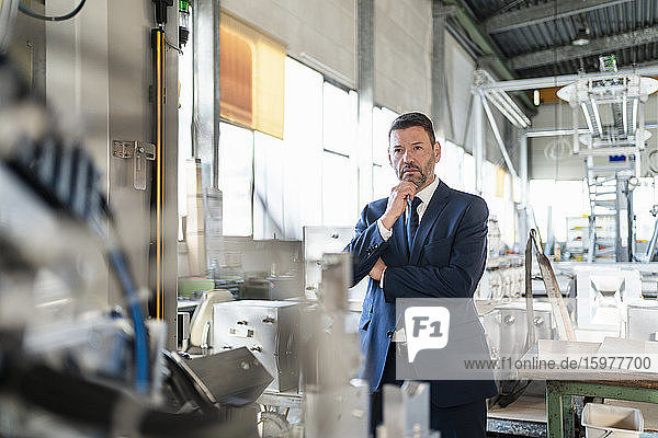 Mature businessman looking at a machine in a factory