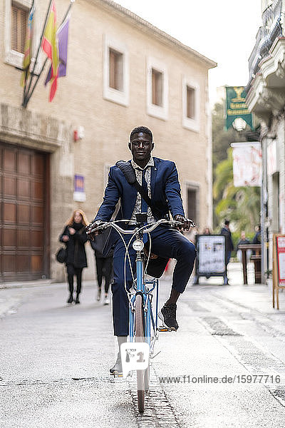 Porträt eines jungen Geschäftsmannes beim Fahrradfahren in der Stadt