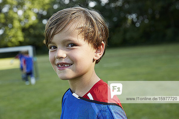 Close-up portrait of happy soccer boy on field