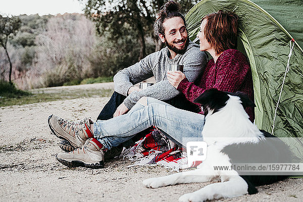 Glückliches Paar mit Hund beim Camping auf dem Lande