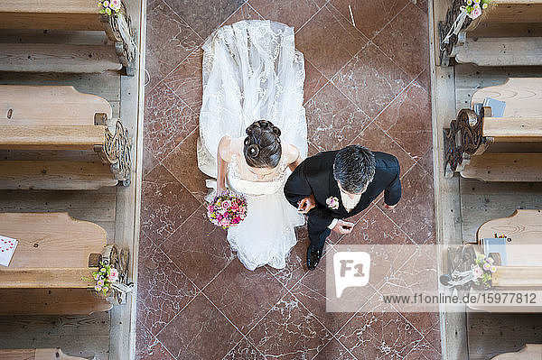 Newlywed couple walking on tiled floor in church