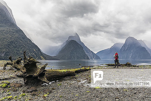 New Zealand  Oceania  South Island  Southland  Fiordland National Park  Woman standing at Milford Sound  Mitre Peak in background