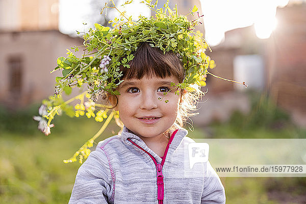 Close-up of smiling cute preschool girl wearing plant crown while standing at orchard