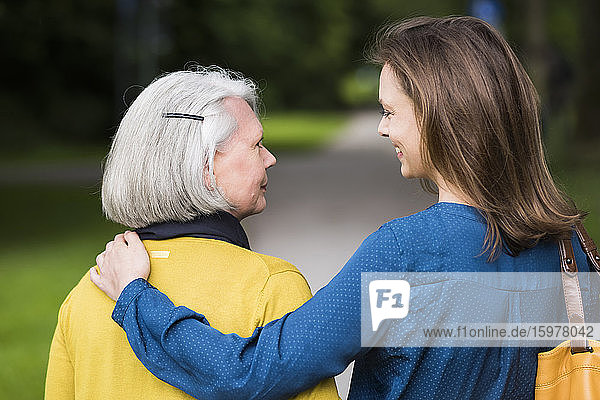 Ältere Frau und erwachsene Tochter schauen sich in einem Park an