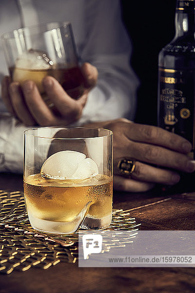 Scotch mit Eis  Männerhände im Hintergrund