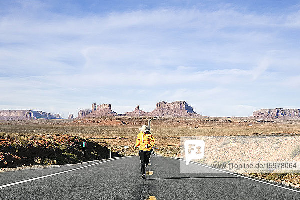 Frau läuft in voller Länge auf Wüstenstraße gegen Himmel  Monument Valley Tribal Park  Utah  USA