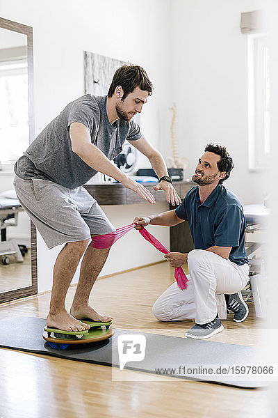 Physiotherapeutin hilft Patientin beim Üben auf dem Balancetrainer