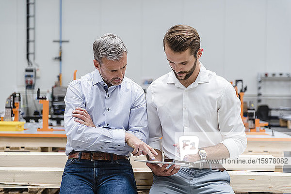 Zwei Männer teilen sich ein Tablet in einer Fabrikhalle