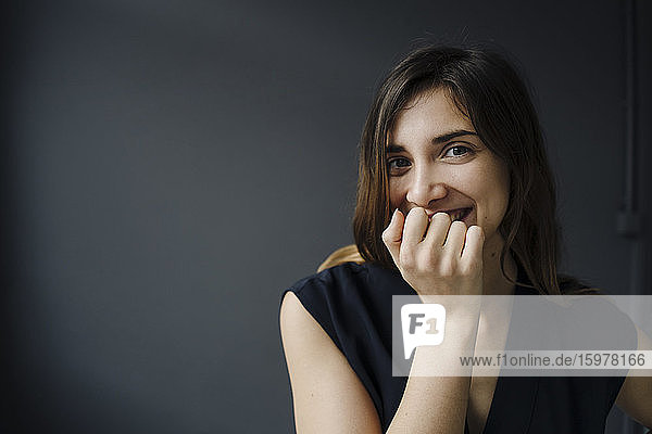 Porträt einer lachenden jungen Frau mit Hand vor dem Mund