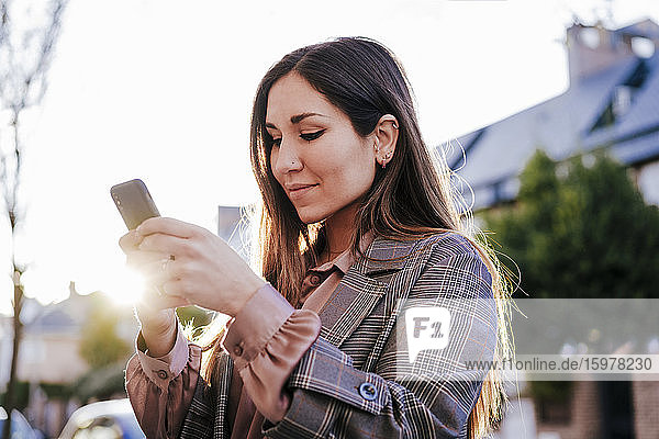 Portrait of woman looking at cell phone at backlight