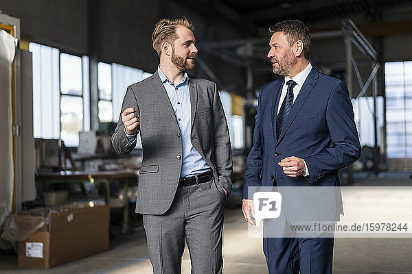 Two businessmen walking and talking in a factory