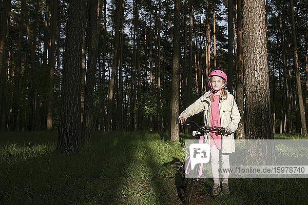 Mädchen stehend mit Fahrrad im Wald