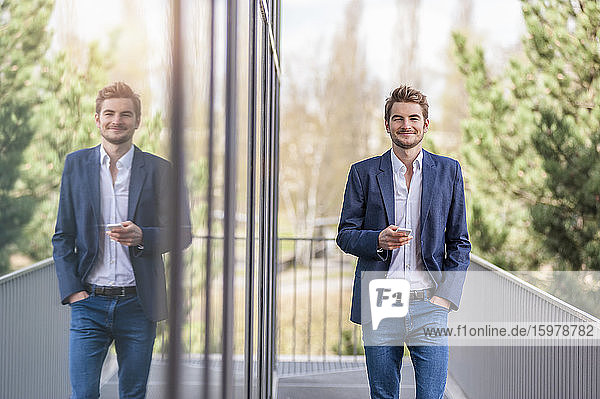 Junger Geschäftsmann mit Smartphone in einem Bürogebäude