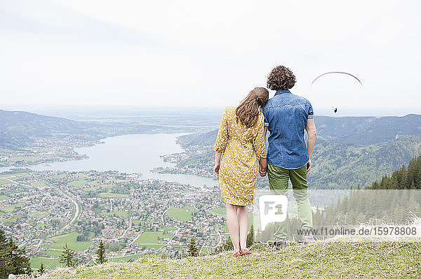 Mid adult couple holding hands while looking at landscape from mountain peak