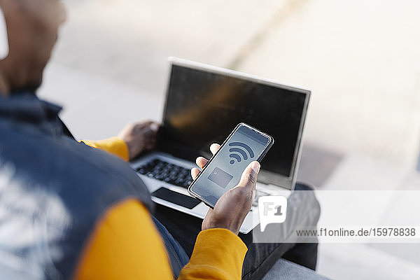 Nahaufnahme eines Mannes  der Laptop und Smartphone zum Online-Shopping benutzt