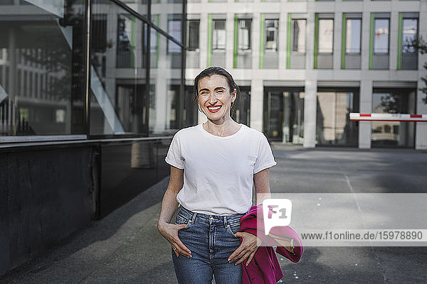 Happy businesswoman standing outside office building