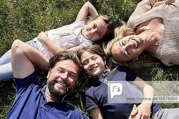 Glückliche Familie im Gras liegend an einem sonnigen Tag