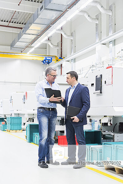 Two businessmen having a discussion in a factory